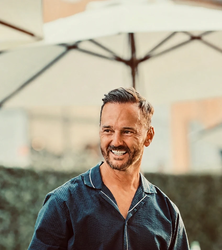 Dr Michael Welch OBE FRSE outdoors, smiling, in a navy short-sleeved shirt.